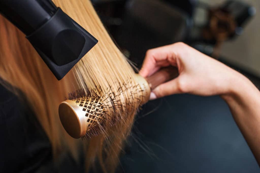 femme dans un salon de coiffure - séchage à la main cheveux blonds avec sèche-cheveux 