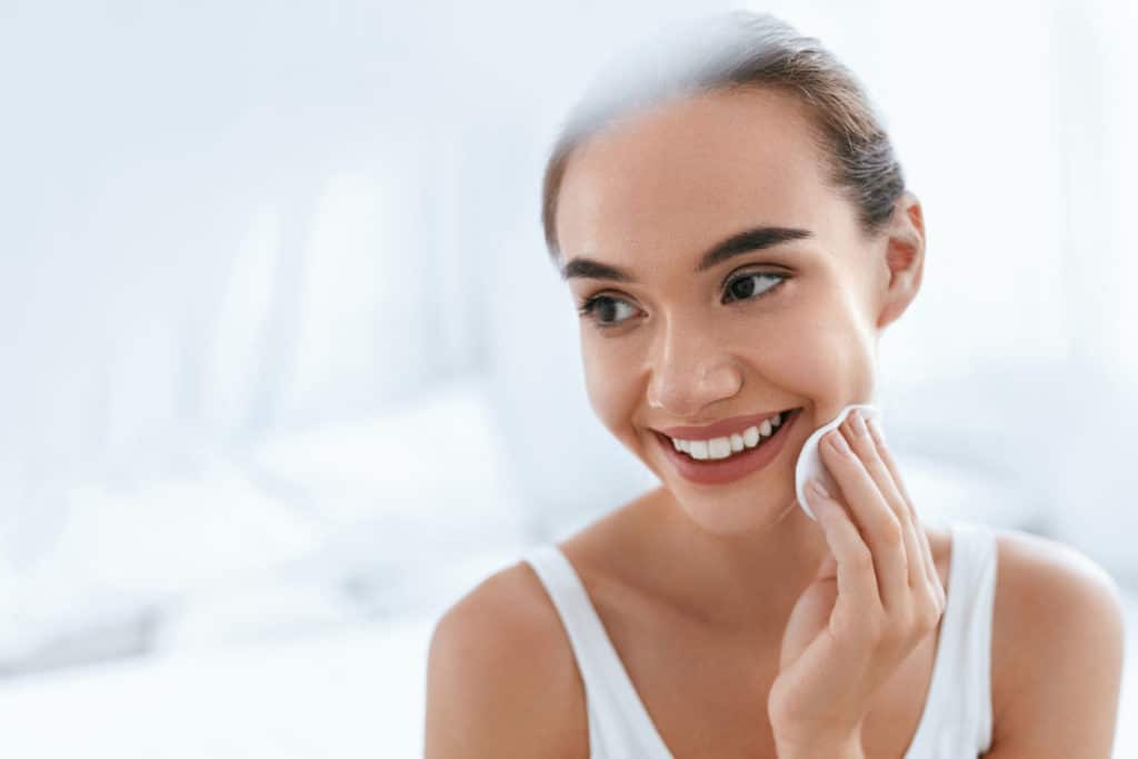 Fille nettoyant visage peau avec cosmétique