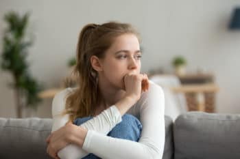 Femme inquiete assis sur le canapé seul à la maison