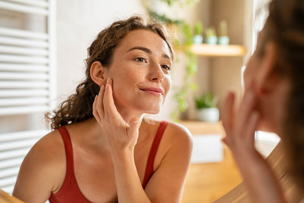 Jeune femme de beauté vérifiant son acne au miroir le matin