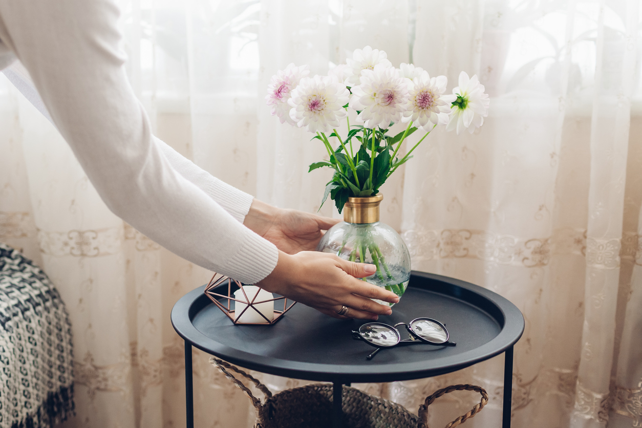 femme met le vase avec des dahlias de fleurs sur la table