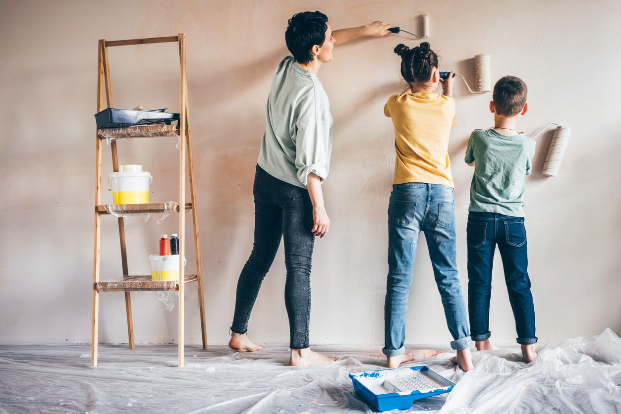 Mère heureuse, fille et fils peinture mur avec rouleau