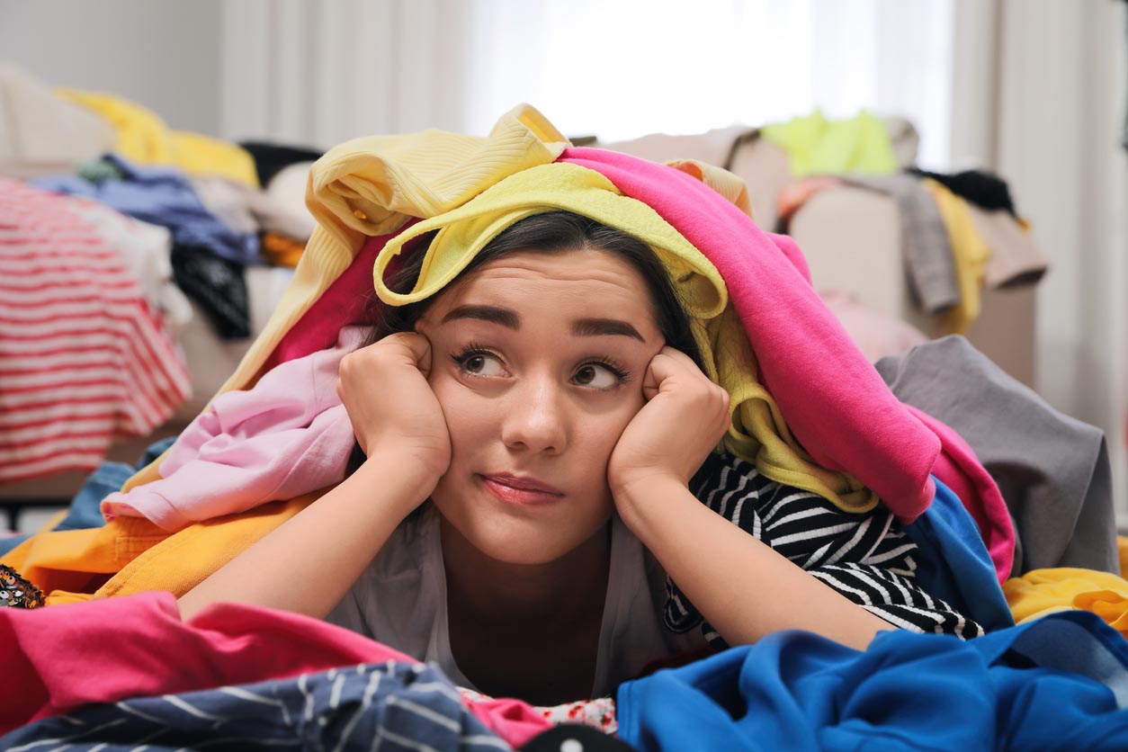 Jeune femme pensive avec beaucoup de vêtements