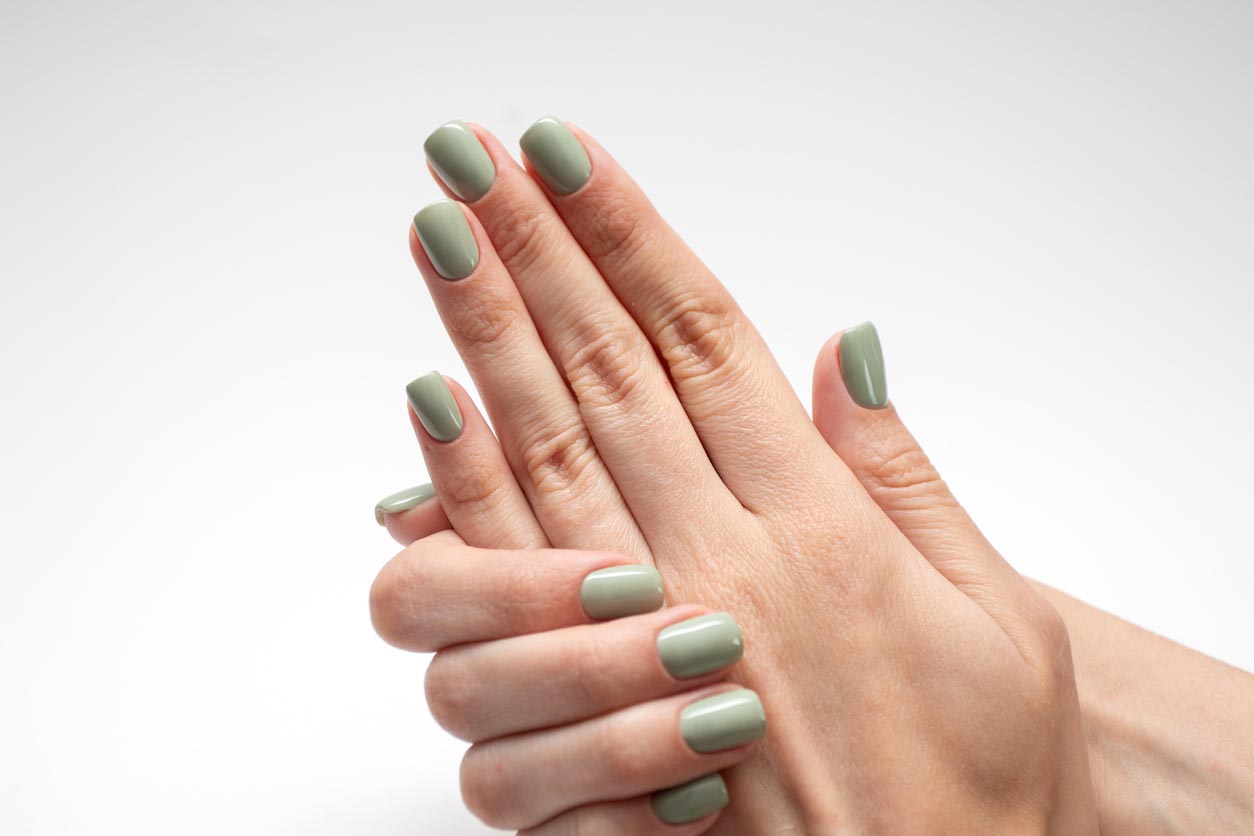 Main de femme avec ongles vert olive