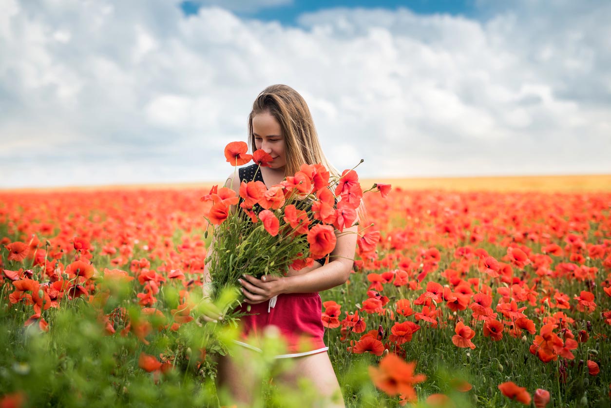 femme tenant un bouquet de coquelicots dans un champs