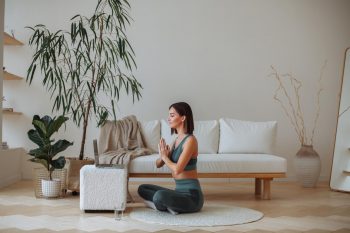 Une jeune femme pratique la méditation à la maison en survêtement