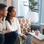 Photo d’un jeune couple heureux assis ensemble lors d’une consultation avec un psychologue
