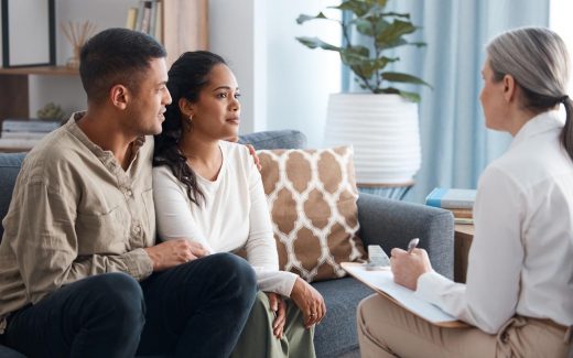 Photo d’un jeune couple heureux assis ensemble lors d’une consultation avec un psychologue