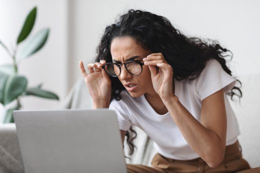 Femme avec une mauvaise vue regarde son ordinateur avec difficultés