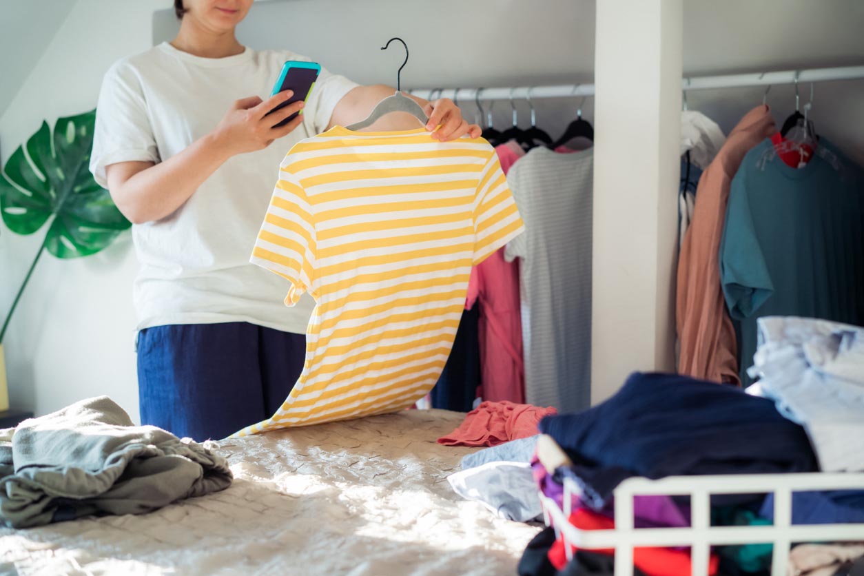 Femme prenant une photo de t-shirt à l’aide de son smartphone pour vendre ou donner ses vêtements