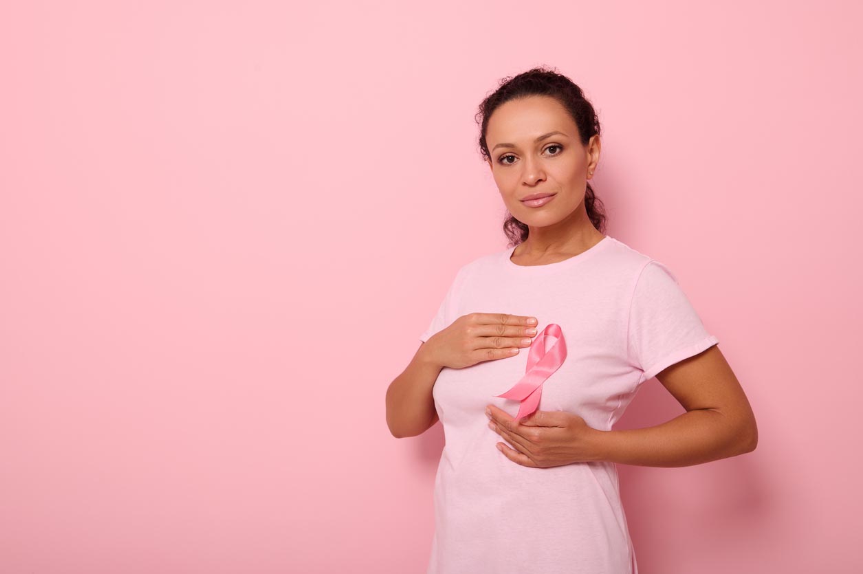 Une femme met les mains autour d’un ruban rose sur son T-shirt rose