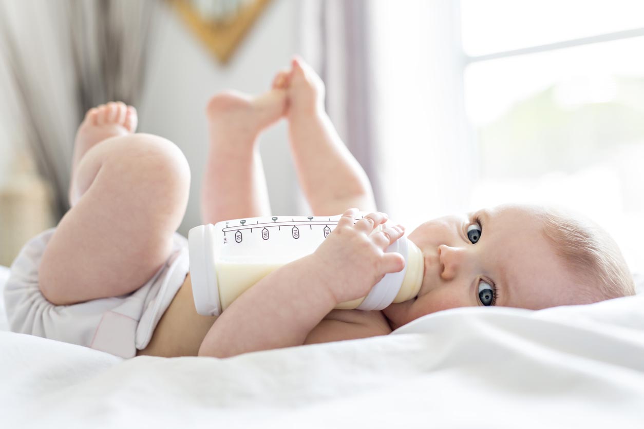 Bébé allongé avec un biberon de lait dans les mains