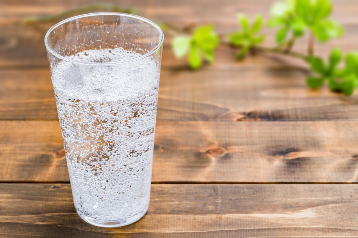 Verre d'eau gazeuse posé sur une table en bois