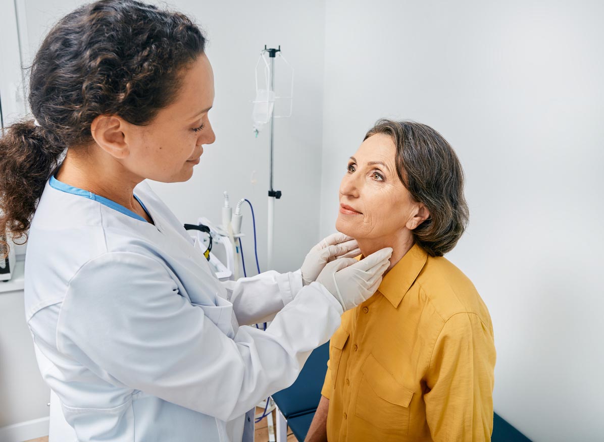 Le médecin palpe le cou de la femme mature pour le diagnostic des maladies thyroïdiennes