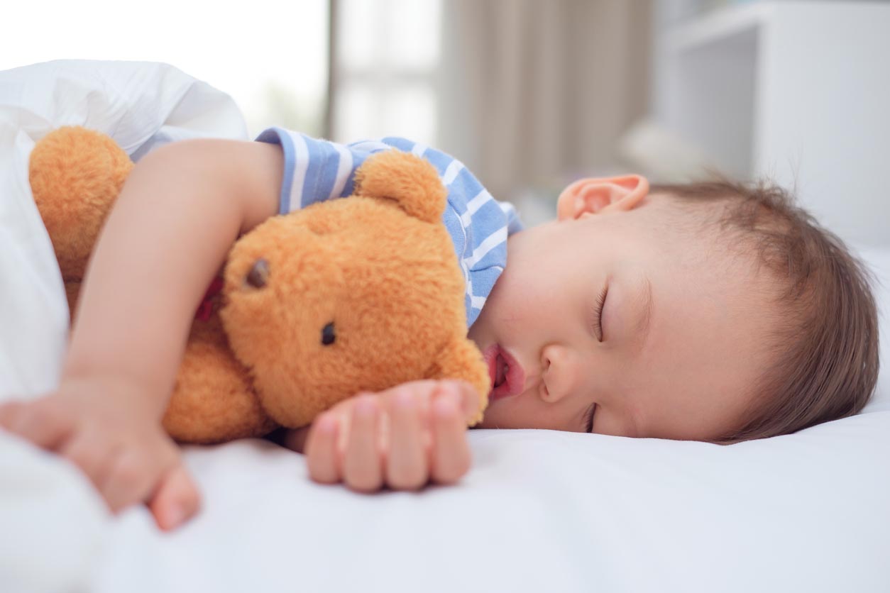 Un enfant dort avec son doudou