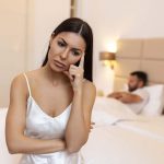 femme embêtée assise sur le lit