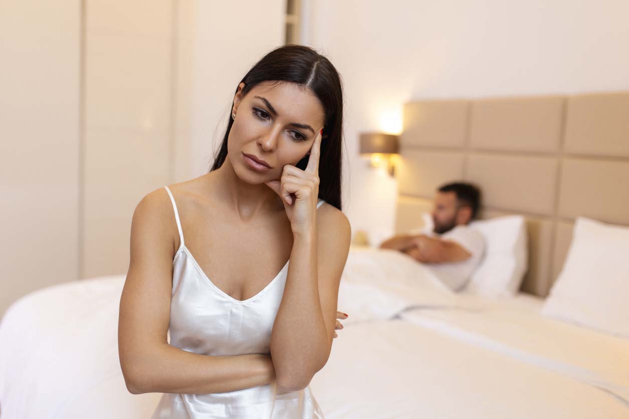femme embêtée assise sur le lit