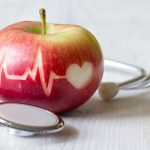 Ligne de battement de cœur sur pomme rouge et stéthoscope, concept de régime cardiaque sain
