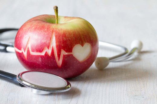 Ligne de battement de cœur sur pomme rouge et stéthoscope, concept de régime cardiaque sain