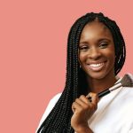 femme afro-américaine souriante avec un pinceau de maquillage