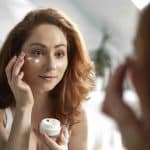 Jeune femme se mettant de la creme sur le visage
