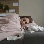 femme malade endormie dans son lit avec des mouchoirs