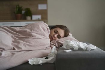 femme malade endormie dans son lit avec des mouchoirs