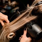 Gros plan sur les mains d'une coiffeuse en plein brushing