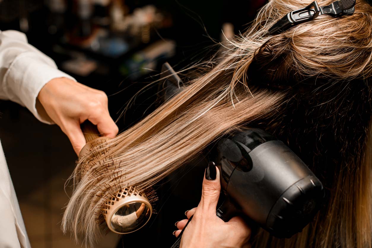 Gros plan sur les mains d'une coiffeuse en plein brushing