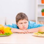 Un enfant en surpoids hésite entre deux plats