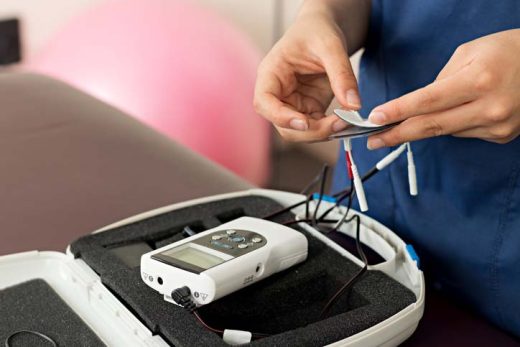 Mains d’un physiothérapeute préparant un appareil d’électrothérapie