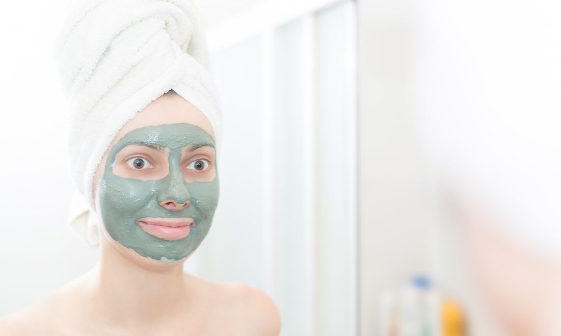 Femme Se Regarde Dans Le Mirroir Avec Son Masque à L'argile Verte