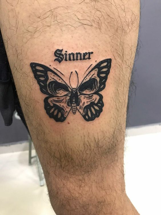 Tatouage Papillon Avec Tête De Mort Et Mot Inspirant Sur La Cuisse 