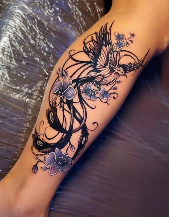 Tatouage Phœnix Avec Queue Arabesque Et Fleurs Sur La Jambe