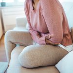 femme sur un canapé souffrant de maux de ventre