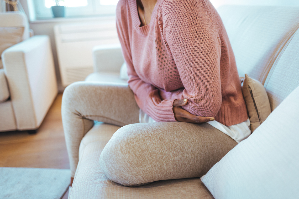 femme sur un canapé souffrant de maux de ventre