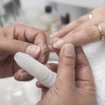 Une manucure place une extension d’ongle claire au doigt