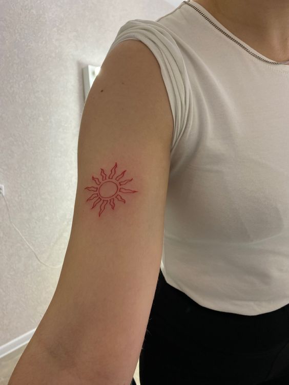 Tatouage Petit Soleil à L'encre Rouge Sur Le Bras