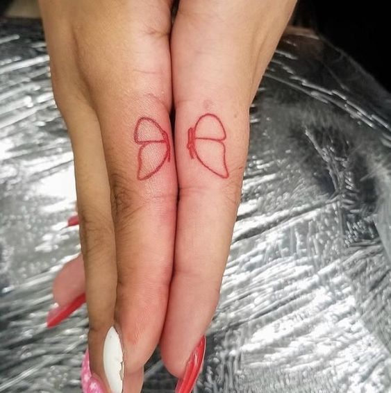 Tatouage Moitié De Papillon à L'encre Rouge Sur Les Doigts