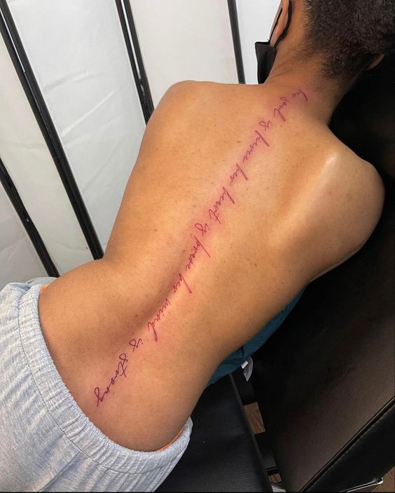 Tatouage Phrase Inspirante à L'encre Rouge Sur La Colonne Vertébrale