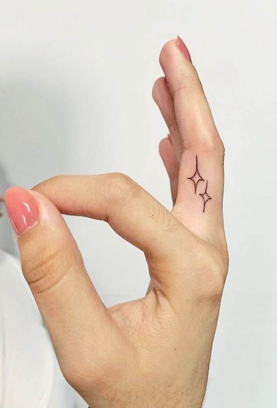 Tatouage Deux étoiles à Quatre Branches Sur Le Doigt