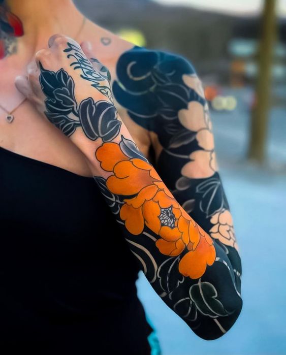 Tatouage Fleurs Orange Avec Fond Noir Sur L'avant Bras