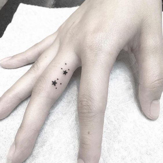 Tatouage étoiles à Cinq Branches Et Points Noirs Sur Le Doigt