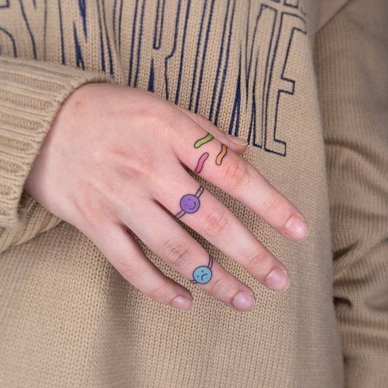 Tatouage Smiley Et Bandes Colorées Sur Le Doigt