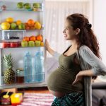 femme enceinte s'interrogeant devant un frigo