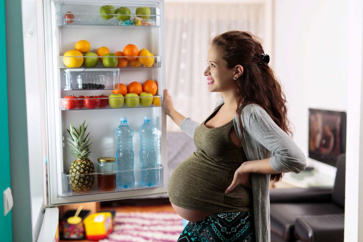 femme enceinte s'interrogeant devant un frigo