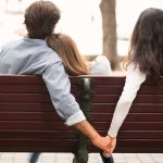 un homme et deux femmes de dos sur un banc, concept d'infidélité