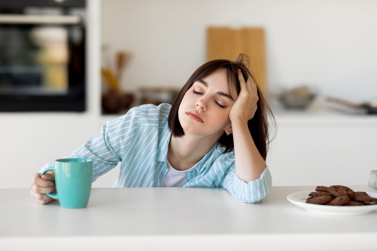 Jeune femme endormie buvant du café, se sentant fatiguée