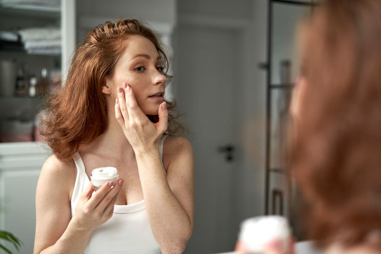 Femme utilisant de la crème pour le visage dans la salle de bain