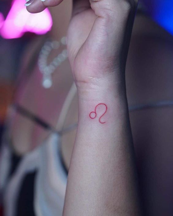 Tatouage Signe Lion à L'encre Rouge Sur Le Poignet